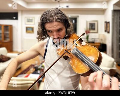 Young handsome man playing violin at home Stock Photo