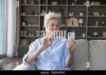 Smiling mature female make video call using smartphone Stock Photo