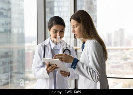Multiethnic Indian and Caucasian doctor colleague women consulting medical records Stock Photo