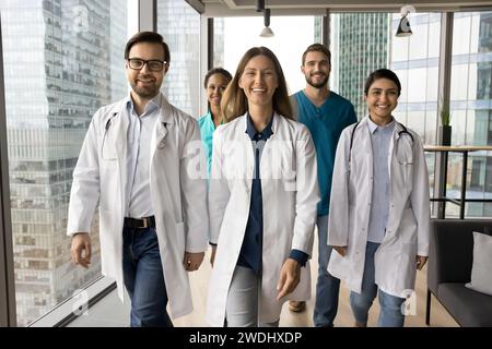 Happy clinic diverse team in uniforms walking in clinic hall Stock Photo
