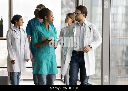 Diverse couple of young doctors walking in clinic office hall Stock Photo
