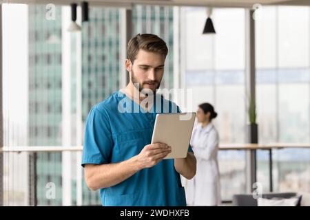 Serious handsome doctor man using medical online application on tablet Stock Photo