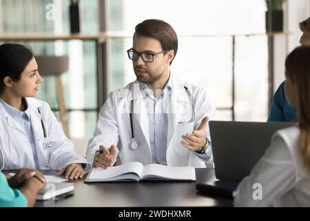Serious male chief doctor in glasses speaking at meeting Stock Photo