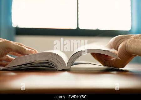 a man reading a book with window light Stock Photo