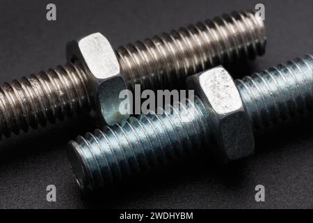 Two oxidized bolts with nuts close-up on a dark background. Macro photography Stock Photo