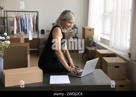 Female warehouse worker, designer working on-line using laptop Stock Photo