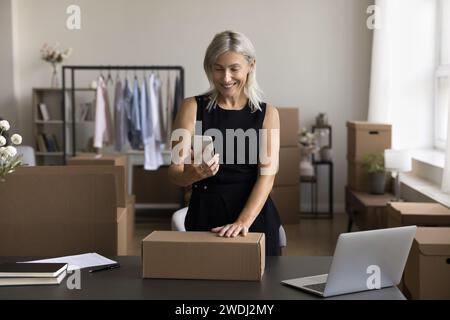 Female designer, own brand founder use mobile app in office Stock Photo