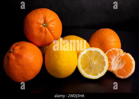 Lemons and mandarins on a black background. Healthy fruits. Detox. Citrus in the kitchen. Body cleansing. Stock Photo