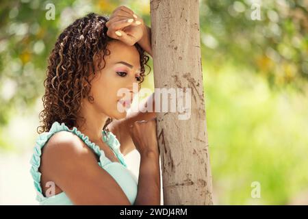 Sad woman leaning against tree Stock Photo
