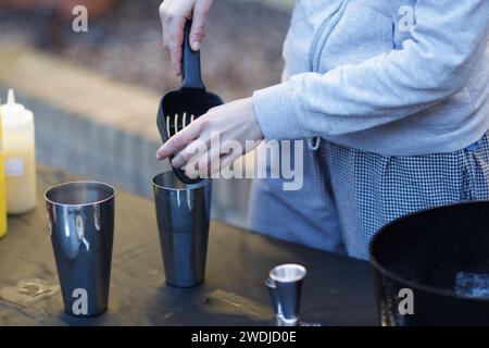 caucasian young cool red haired barista mixing a a cocktail in shaker with energy outdoors in private event in winter time Stock Photo