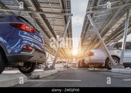 Solar panels installed over parking lot with parked cars for effective generation of clean energy. Stock Photo