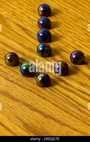 A group of marbles forming an arrow on a wooden game board. Stock Photo