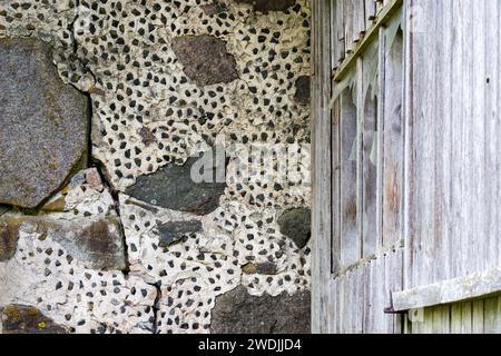 stone wall of a boulder building with small embedded stones Stock Photo