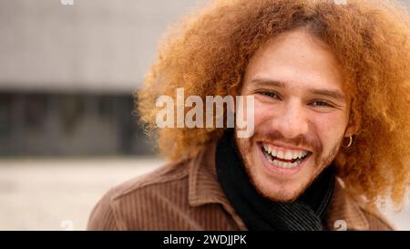 Young man with curly hair smiling at camera Stock Photo