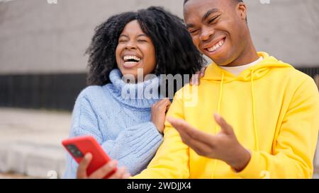 African couple having fun using mobile in the street Stock Photo