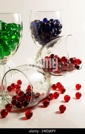 Red, blue, and green marbles in wine glasses. Stock Photo