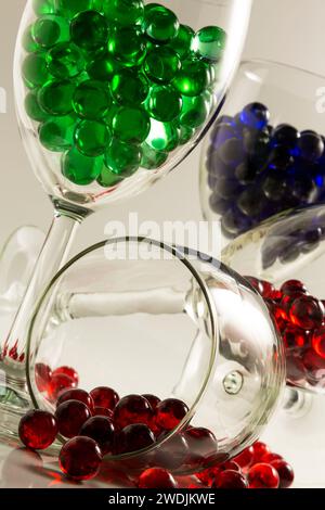 Red, blue, and green marbles in wine glasses. Stock Photo