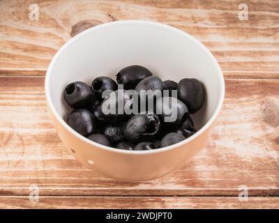 A bowl of black olives on a rustic wooden tabletop Stock Photo