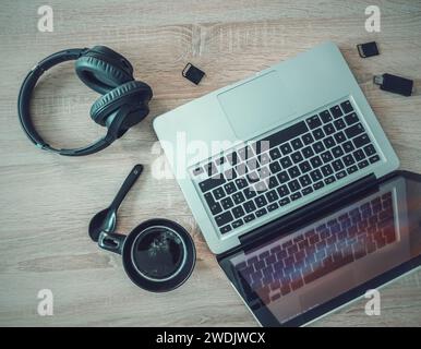 Laptop, coffee cup, headphones and sd cards seen from above Stock Photo