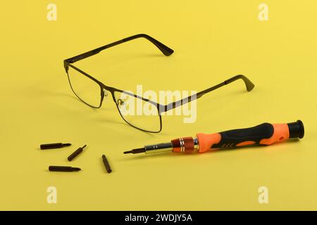 Set of screwdriver bits for repair reading glasses isolated on yellow background. High resolution photo. Full depth of field. Stock Photo