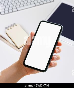 Mockup mobile app digital organizer. Hand holding phone with blank screen in front of diary, digital tablet and pc on the desk. Stock Photo