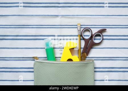 Writing supplies stationery in pencil case on stripe pattern fabric background. top view Stock Photo