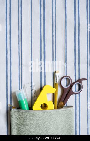 Writing supplies stationery in pencil case on stripe pattern fabric background. top view Stock Photo