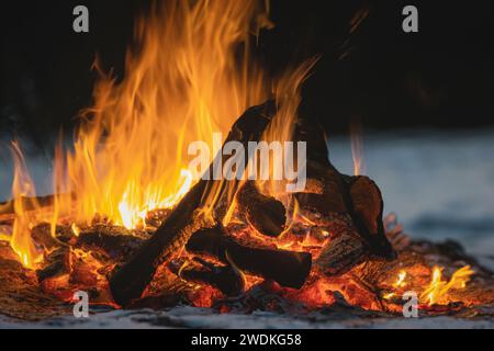 The hearth burns beautifully. Burning wood and hot flames, on a dark background, close-up. A big bonfire made of boards. Firewood in a bright flame. Stock Photo