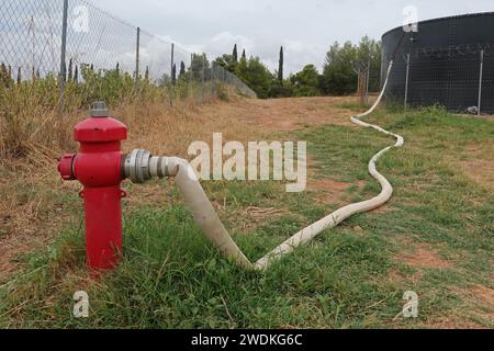 Leaking red fire hydrant and fire hose attached Stock Photo - Alamy