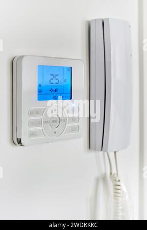 Video intercom with talkback or doorphone voice communications system mounted on wall, close up view. Climate control show 25 degrees indoor, remote a Stock Photo