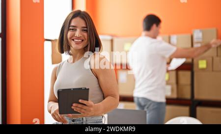 Two workers man and woman using touchpad checking packages smiling at office Stock Photo