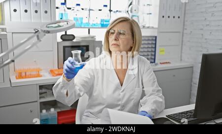 Mature woman scientist conducting research in a laboratory setting, surrounded by equipment. Stock Photo