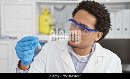 Focused man analyzing a sample in a modern laboratory setting wearing safety goggles and gloves. Stock Photo