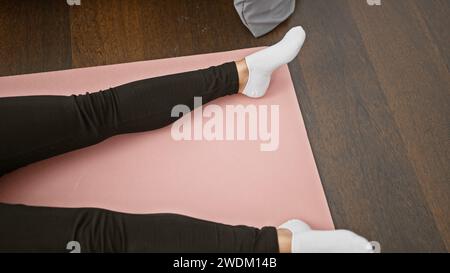 Beautiful blonde woman resting in tranquil morning meditation, lying on yoga mat in bedroom, awakening sensations of relaxation and calm Stock Photo
