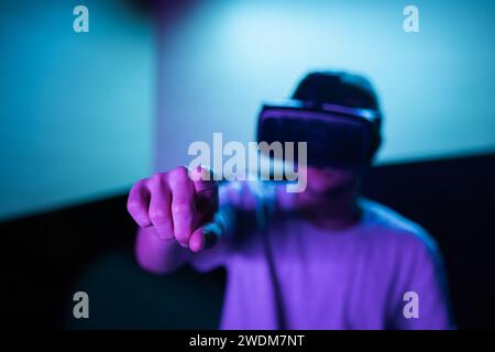 Young man interacting in a digital world, using virtual reality headset with motion tracking tech, making hand gestures in the air. Stock Photo