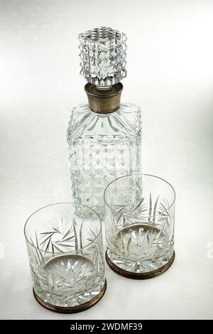 Cut crystal decanter and two carved glasses with silver decoration on the stopper and on the rim of the glasses Stock Photo