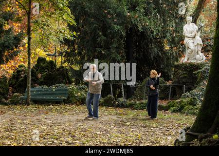 A woman and a man practise tai chi in front of a marble statue in Giardini Indro Montanelli gardens and park, Milan, Milano, Italy Stock Photo