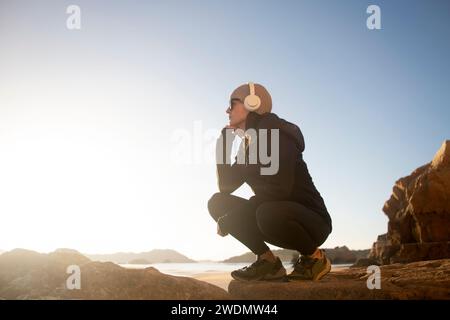 Woman walker resting and enjoying the view while listening to music with headphones. Stock Photo