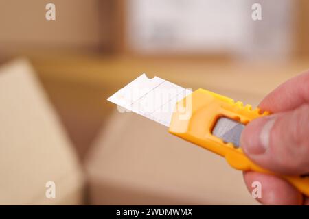 Utility knife or box cutter in hand with retractable segmented blade for parcel unboxing close up Stock Photo