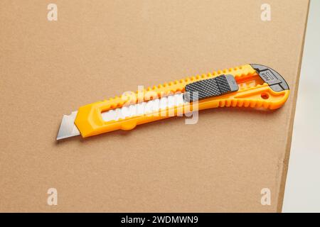 Box cutter on a parcel cardboard box close up. Retractable utility knife Stock Photo