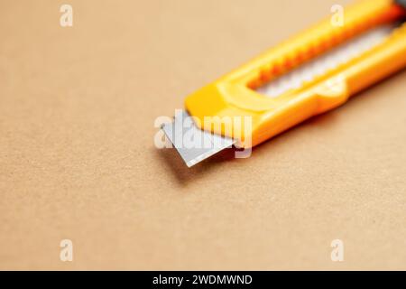 Utility knife or retractable box cutter for parcel unpacking on a brown kraft cardboard background Stock Photo