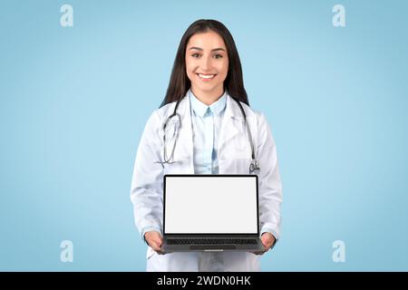 Happy european female doctor showing laptop with blank screen advertising online medical offer or service Stock Photo