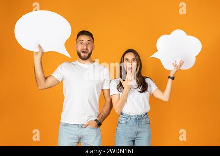 Smiling shocked surprised millennial european couple holds up speech bubbles Stock Photo