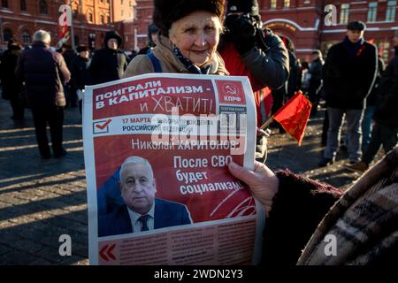 Moscow, Russia. 21st of January, 2024. Russian Communist supporter reads a campaign leaflet of the Nikolai Kharitonov presidential candidate of the Russian Federation as they walk to lay flowers at the Mausoleum of the Soviet founder Vladimir Lenin to mark the 100th anniversary of his death, in Red Square, Moscow, Russia. Credit: Nikolay Vinokurov/Alamy Live News Stock Photo