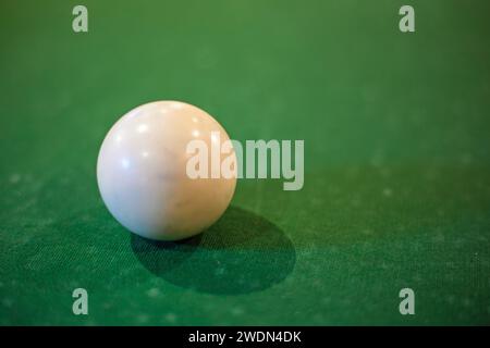 Landscape format close up shot of a white snooker ball on a green baize covered table. Stock Photo