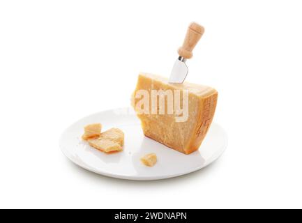 Aged parmesan cheese or parmigiano reggiano and a knife with a wooden handle for cheese on a white plate isolated on a white background. With clipping Stock Photo