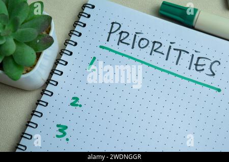 Concept of Priorities write on book. Supported by an additional services isolated on Wooden Table. Stock Photo