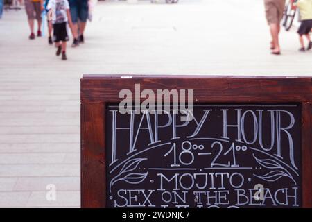 Sign for happy hour for cocktails. Enjoying life with drinks on summer vacation. Drinking alcohol on night out. Positive mood. Good vibes. Urban party Stock Photo