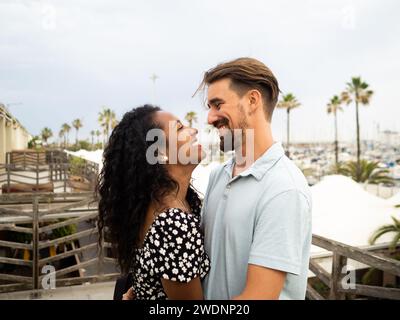 Diverse heterosexual couple looking affectionately at each other in love in a city during vacation Stock Photo