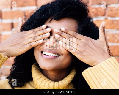 Portrait of a carefree African American woman covering her eyes with her hands Stock Photo